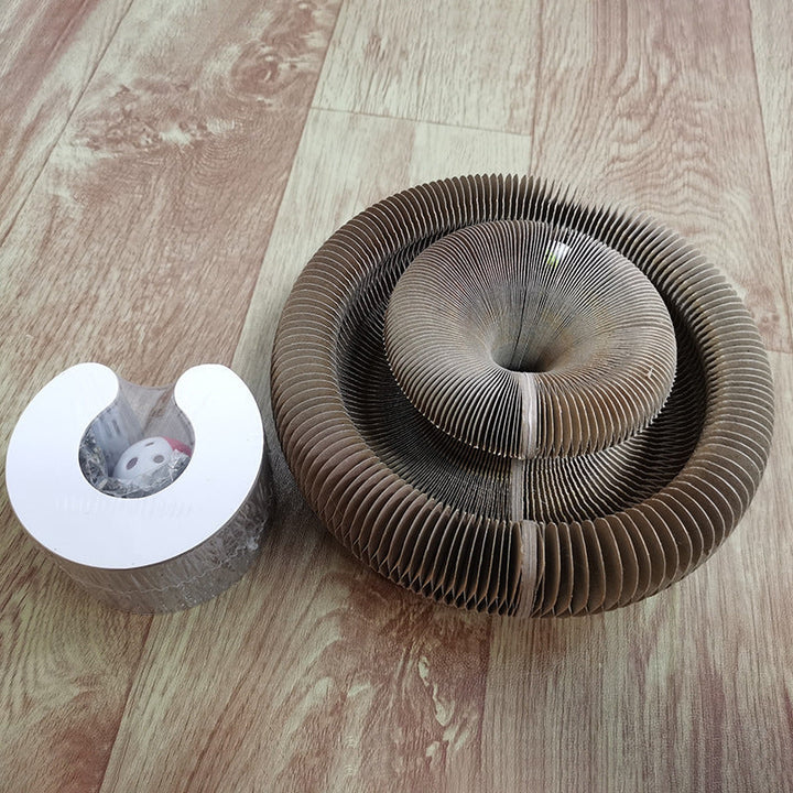 Brauner Katzenkratzer aus Wellpappe auf Holzboden, Spielzeug inklusive.