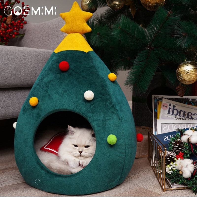 Weiße Katze in grünem Weihnachtsbaum-Katzenbett mit bunten Kugeln, gemütlich und dekorativ.