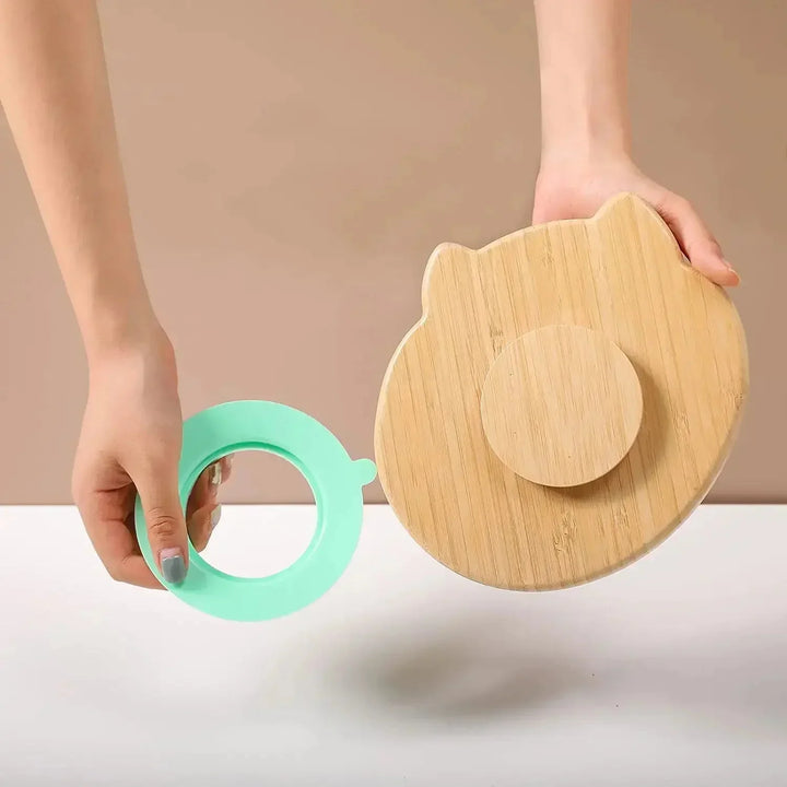 Person hält runden Bambusdeckel mit Katzenohren und grünem Silikonring, Küchendekoration.