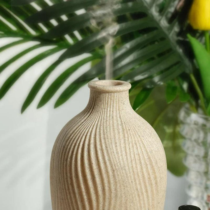 Keramikvase beige, geriffelt, vor grünen Blättern, dekorativ, modern, Wohnzimmer-Dekoration.