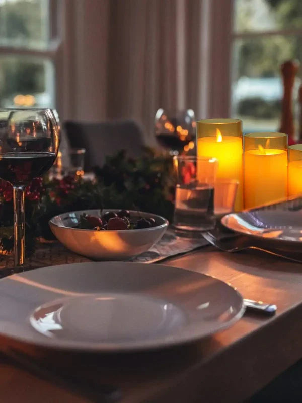 Eleganter Esstisch mit Kerzen, Weingläsern und Geschirr, stimmungsvolle Abendbeleuchtung.