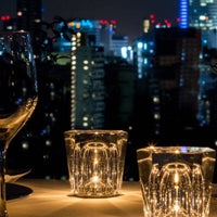 Kristall-Teelichthalter bei Nacht, Stadtlichter im Hintergrund, elegante Tischdekoration.