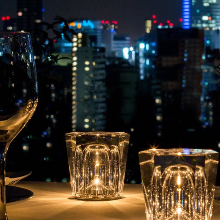 Kristall-Teelichthalter bei Nacht, Stadtlichter im Hintergrund, elegante Tischdekoration.