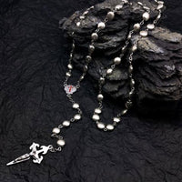 Silberne Rosenkranzkette mit Kreuzanhänger auf schwarzem Hintergrund, religiöser Schmuck.