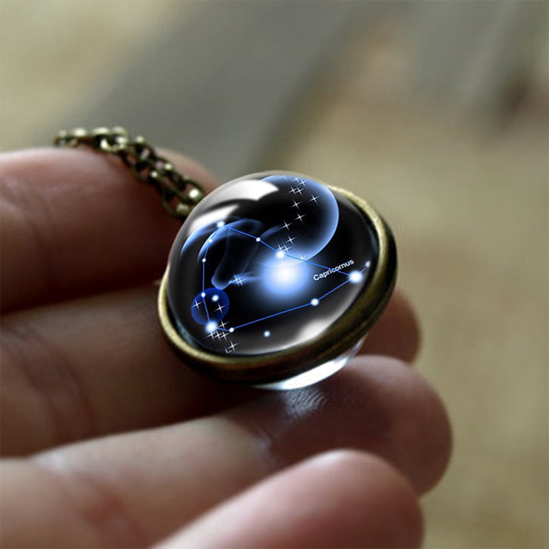 Kette mit Glasanhänger, Sternzeichen Steinbock, leuchtend, Astrologie-Schmuck, Hand gehalten.
