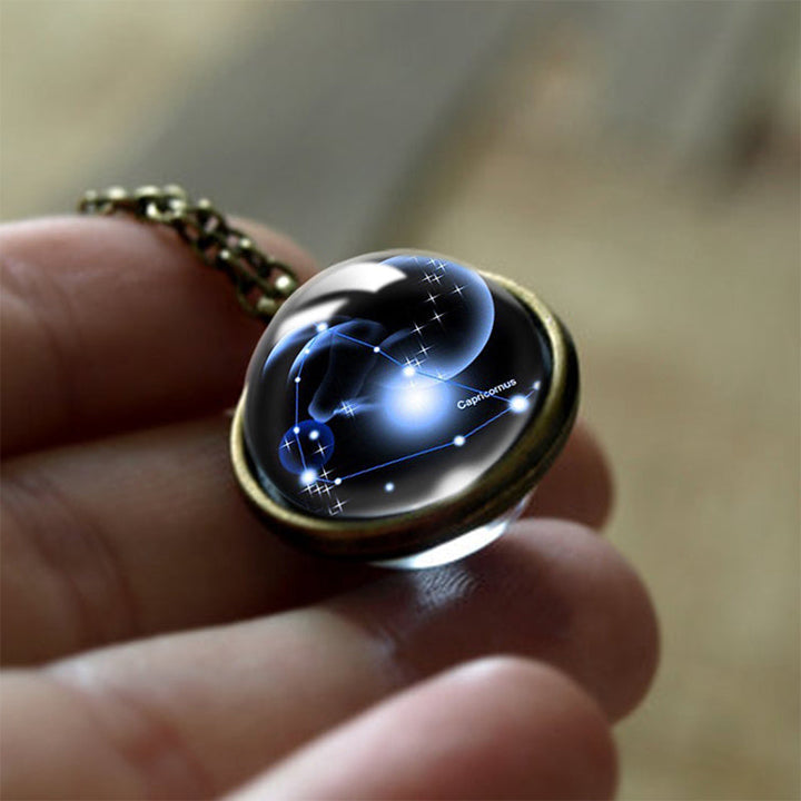 Kette mit Glasanhänger, Sternzeichen Steinbock, leuchtend, Astrologie-Schmuck, Hand gehalten.