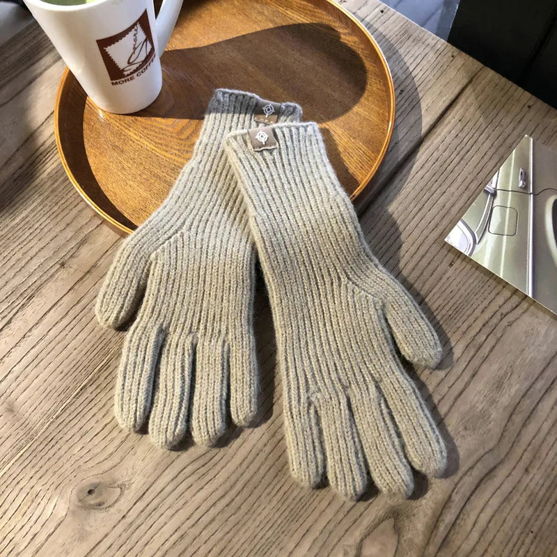 Khaki Strickhandschuhe aus Wolle auf Holztisch, ideal für Wintermode und kaltes Wetter.