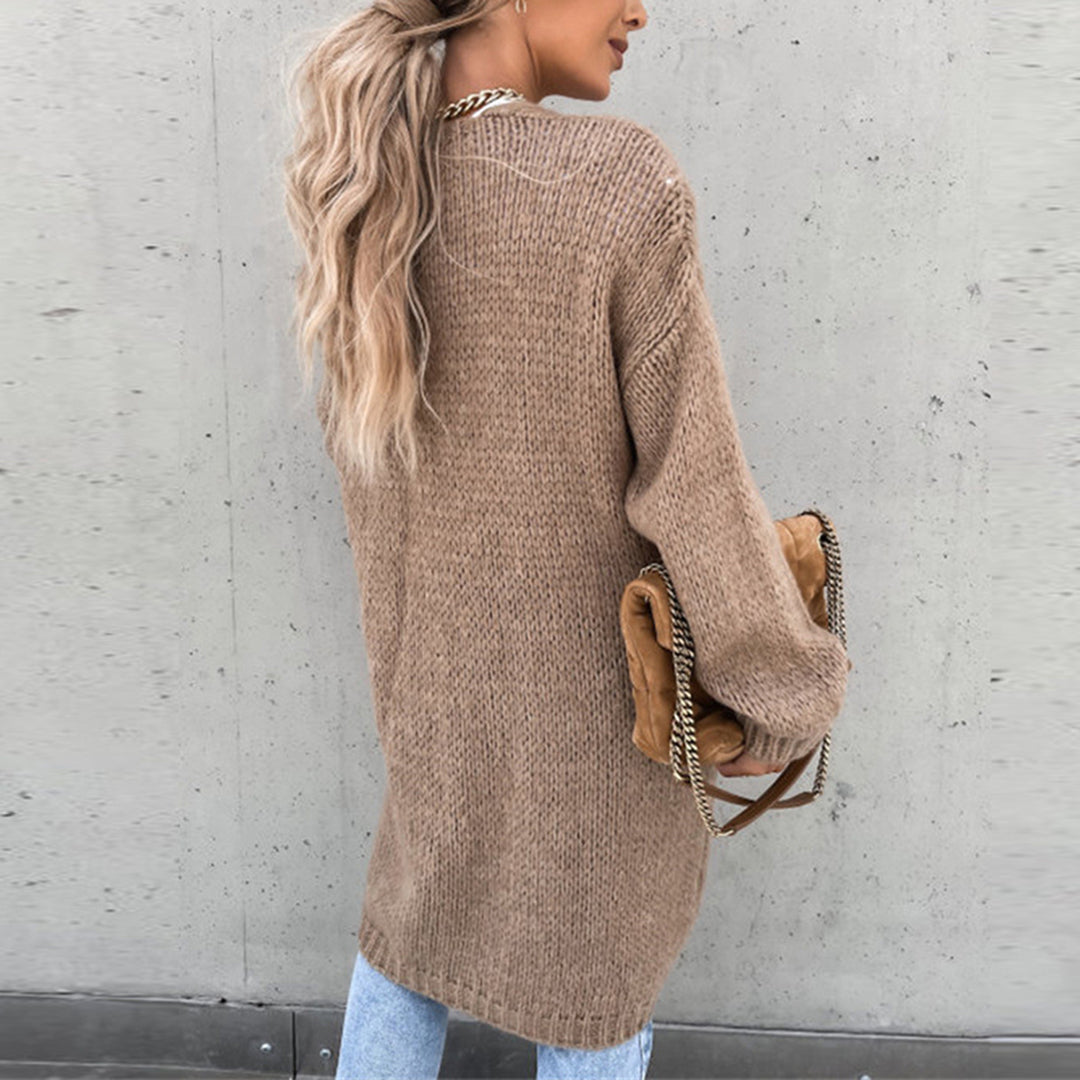 Frau in langem, khakifarbenem Strickpullover mit Tasche, lässiger Herbstlook.