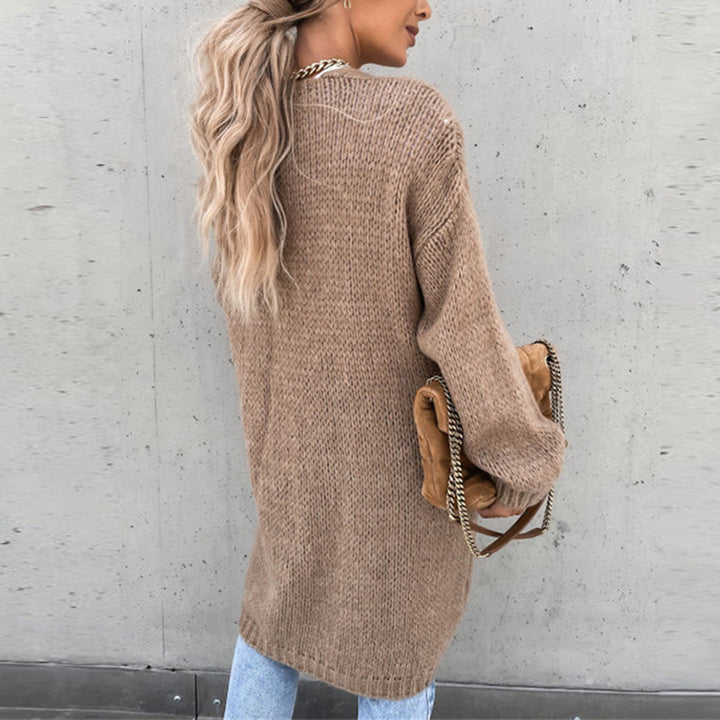 Frau in langem, khakifarbenem Strickpullover mit Tasche, lässiger Herbstlook.