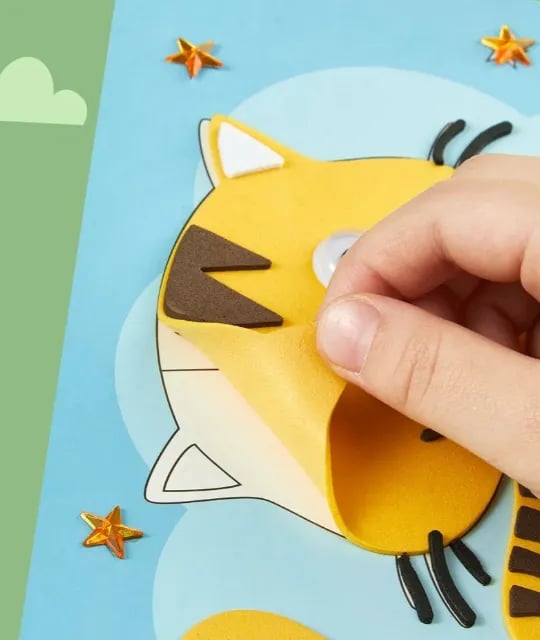 Hand klebt gelben Schaumstoffaufkleber auf Tierbild, DIY Bastelset für Kinder, kreative Aktivität.