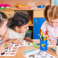 Kinder malen mit Buntstiften und Tieraufklebern im Klassenzimmer. Kreatives Lernen, Grundschule.