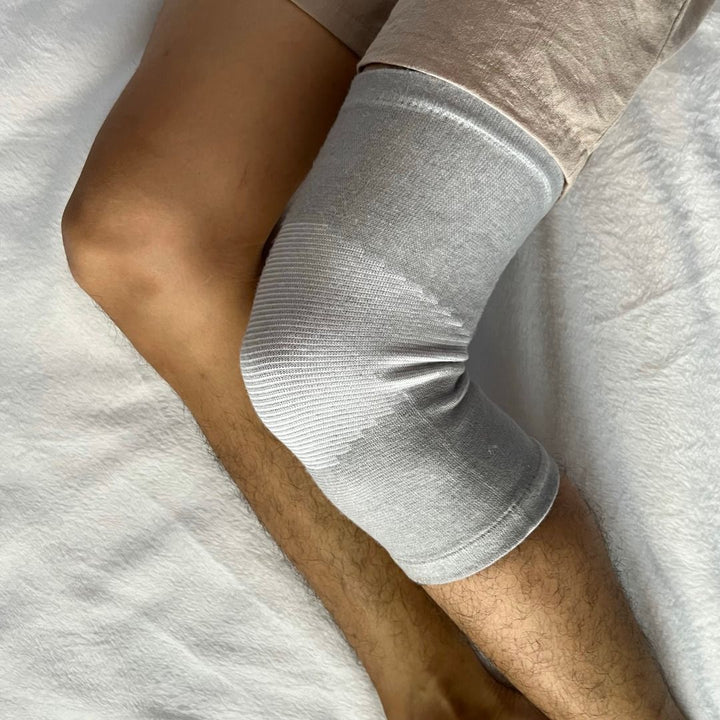 Graue Kniebandage aus elastischem Material für Sport und Erholung auf Bein getragen.