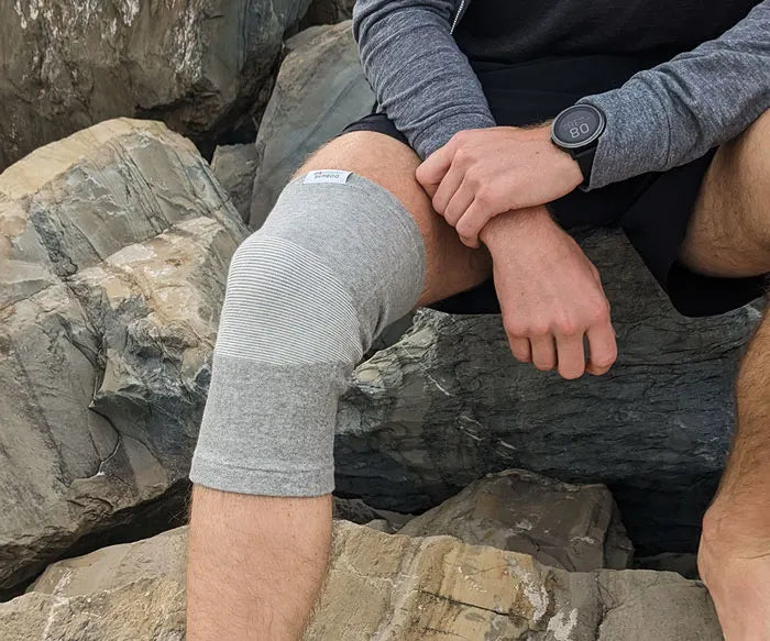 Grau gestreifte Kniebandage aus Baumwolle auf Felsen, ideal für Sport und Erholung.