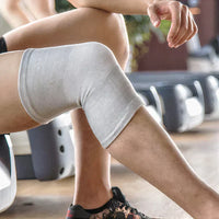Person mit weißer Kniebandage im Fitnessstudio, Sportbekleidung, Rehabilitation, Training.