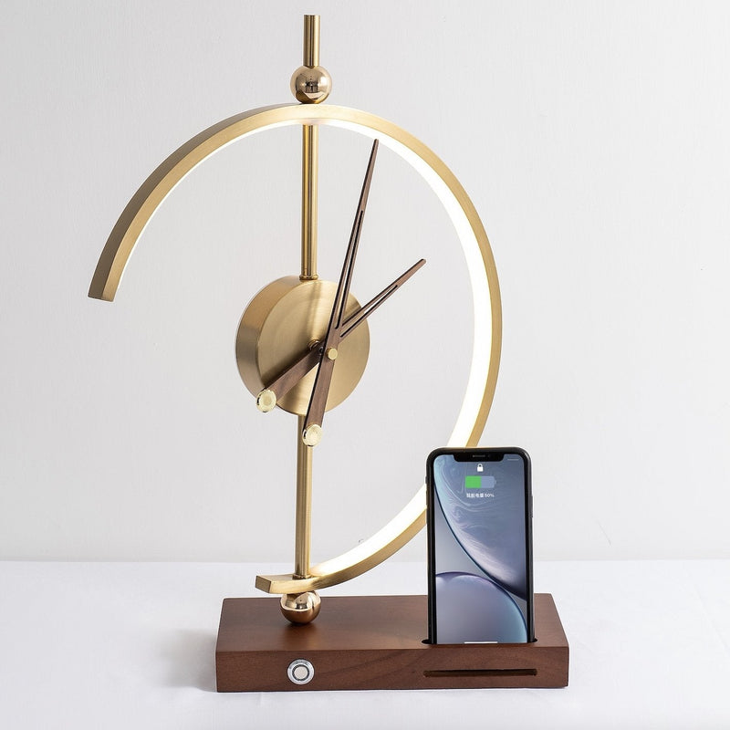 Goldene Tischuhr mit Holzsockel und Smartphone-Ladestation, modernes Design.