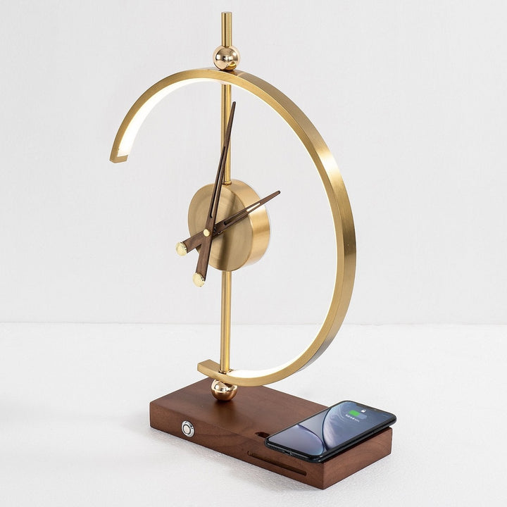 Goldene Designeruhr mit Holzsockel und Smartphone-Ladestation, modern und stilvoll.