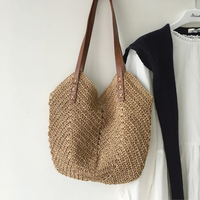 Beige Strohtasche mit braunen Ledergriffen, handgefertigt, ideal für Sommer und Strand.