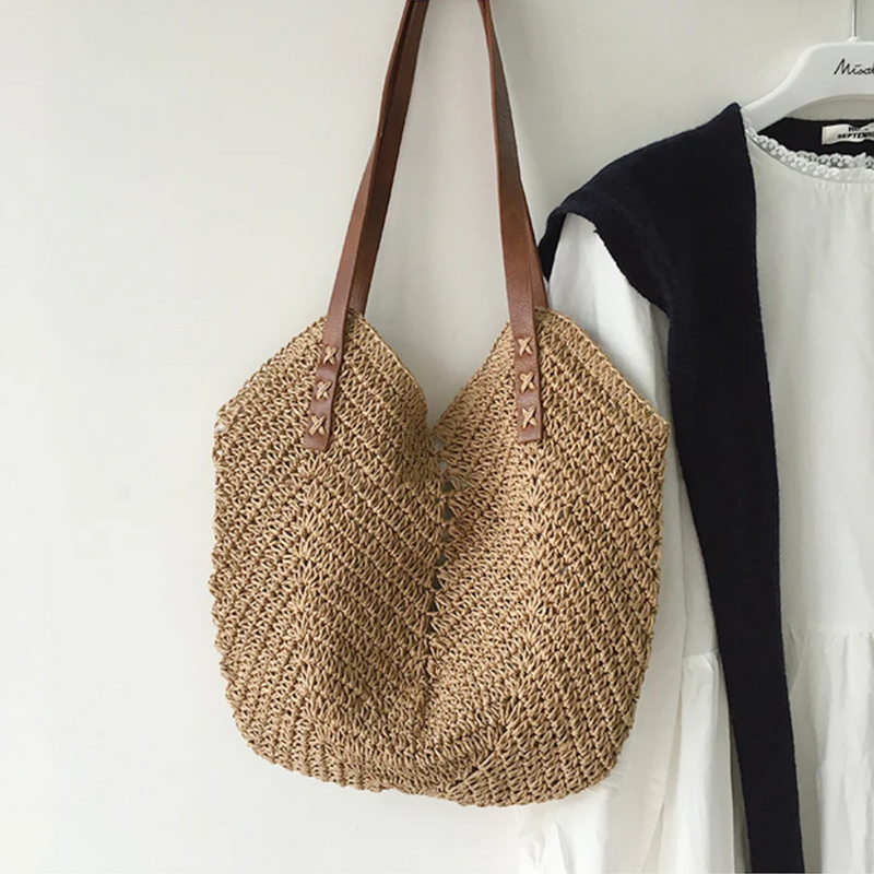 Beige Strohtasche mit braunen Ledergriffen, handgefertigt, ideal für Sommer und Strand.