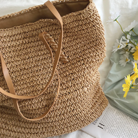 Geflochtene Strohtasche mit Ledergriffen, ideal für Sommer, Strand, Picknick, auf weißem Hintergrund.