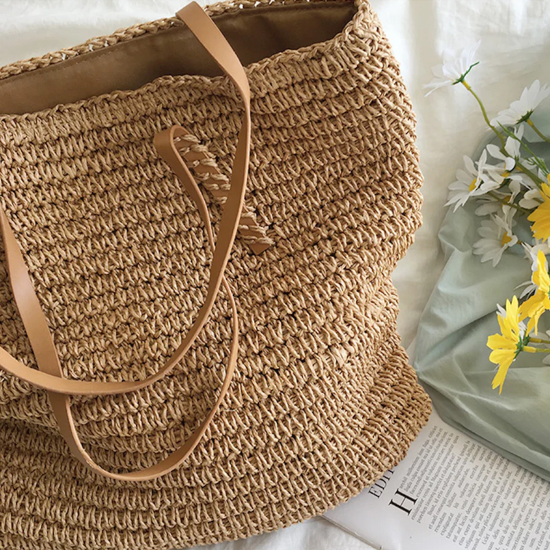 Geflochtene Strohtasche mit Ledergriffen, ideal für Sommer, Strand, Picknick, auf weißem Hintergrund.