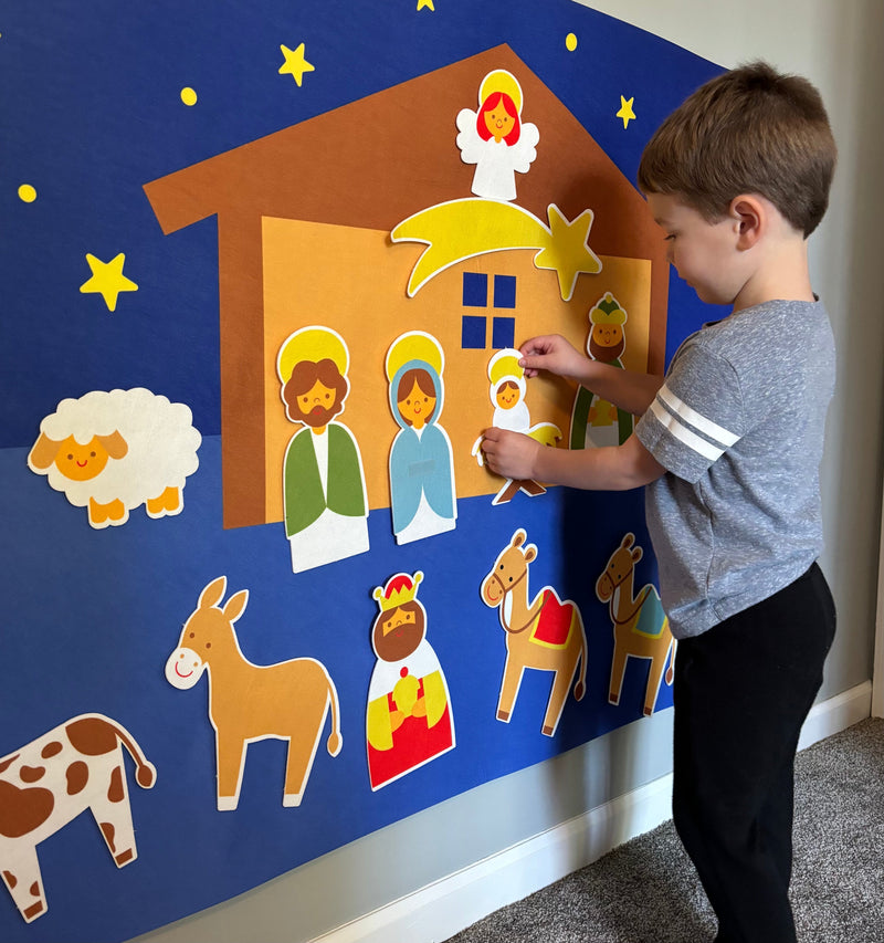 Kind spielt mit Krippenfiguren an Wand, Weihnachtsdekoration, pädagogisches Spielzeug.