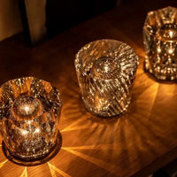 Drei kristallene Teelichthalter auf Holzoberfläche, warmes Licht, dekorative Beleuchtung.