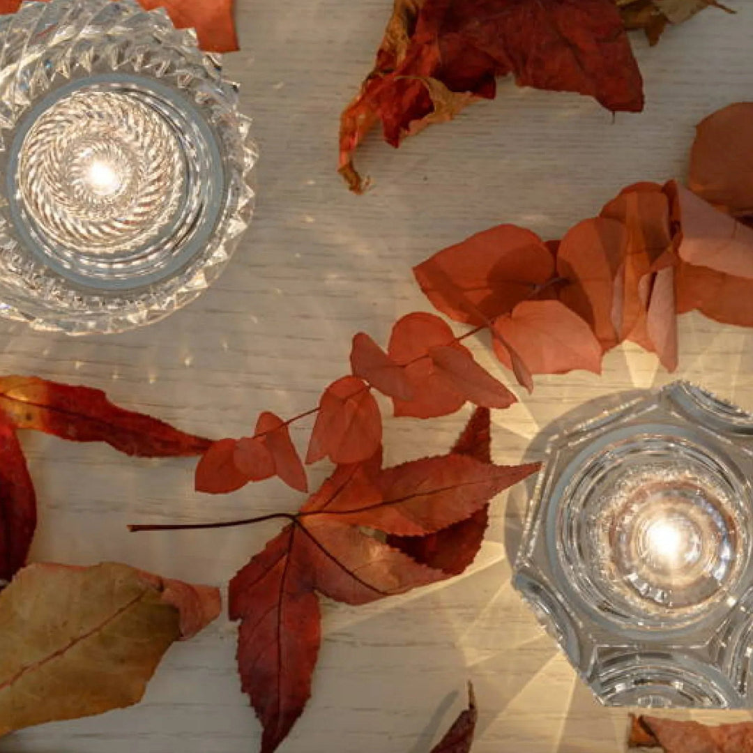 Kristallkerzenhalter auf Holztisch mit Herbstblättern, dekorative Beleuchtung, elegant, stilvoll.