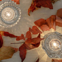 Kristallkerzenhalter auf Holztisch mit Herbstblättern, dekorative Beleuchtung, elegant, stilvoll.