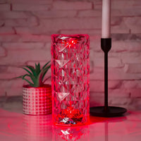Roter Kristallglas-Vase mit geometrischem Muster, dekorativ, modern, auf Tisch neben Kerze.