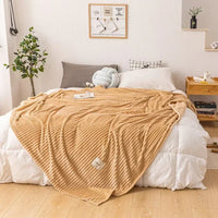 Beige Kuscheldecke aus Fleece auf Bett, gemütliches Schlafzimmer, moderne Inneneinrichtung.