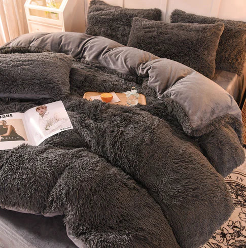 Graues, flauschiges Bettwäsche-Set aus Kunstfell, gemütlich und luxuriös, mit Kissen und Decke.