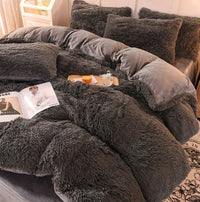 Graues, flauschiges Bettwäsche-Set aus Kunstfell, gemütlich und luxuriös, mit Kissen und Decke.