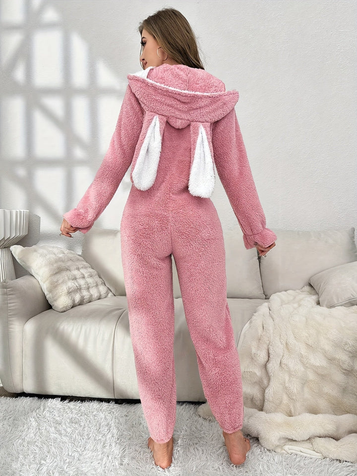 Frau im rosa Plüsch-Einteiler mit Kapuze und Hasenohren, gemütliche Loungewear.