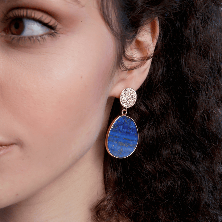Frau mit blauem Lapis-Lazuli-Ohrring, oval, goldgefasst, eleganter Schmuck.