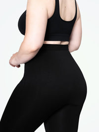 Frau in schwarzer, figurbetonter Leggings und Sport-BH, seitliche Ansicht.
