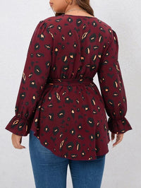 Frau in roter Leopardenbluse mit langen Ärmeln und blauer Jeans von hinten.