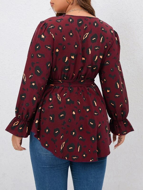 Frau in roter Leopardenbluse mit langen Ärmeln und blauer Jeans von hinten.