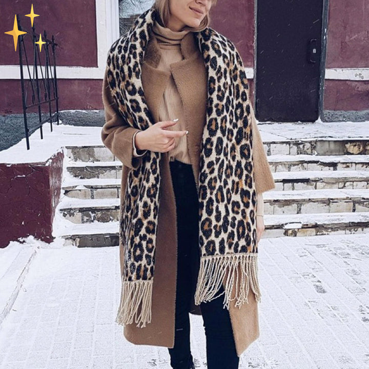 Frau mit Leopardenmuster-Schal und braunem Mantel im Schnee, Wintermode-Trend.