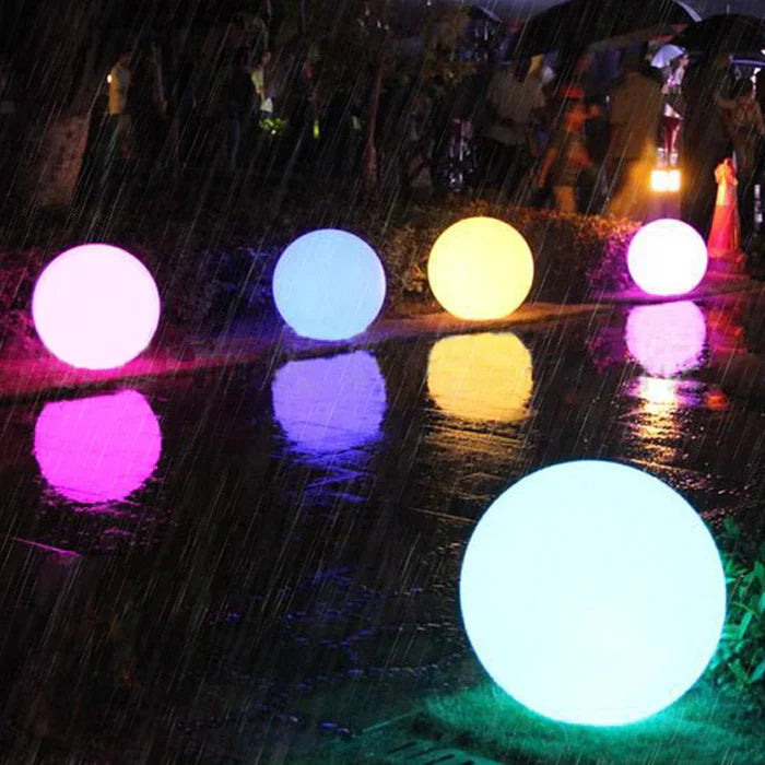Leuchtende LED-Kugeln im Regen, bunte Gartenbeleuchtung, wasserdicht, stimmungsvoll, Nacht.