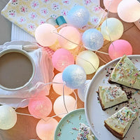 Kaffee und Kuchen mit pastellfarbenen Lichterketten, gemütliche Atmosphäre, Dessert, Beleuchtung.