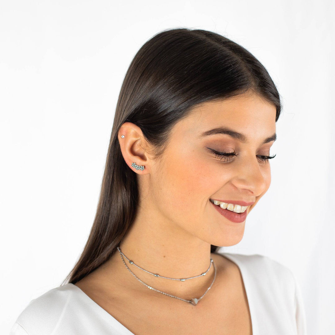 Frau mit silberner Halskette und Ohrringen, lächelnd, Schmuck, Modeaccessoire, stilvoll.