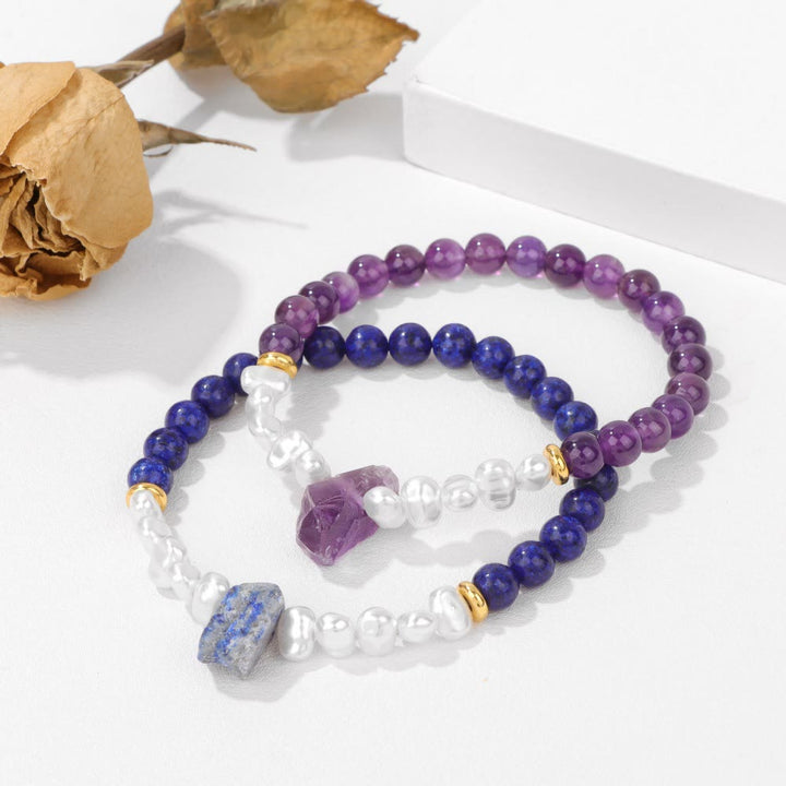 Zwei Armbänder aus Amethyst und Lapislazuli mit Perlen auf weißem Hintergrund.