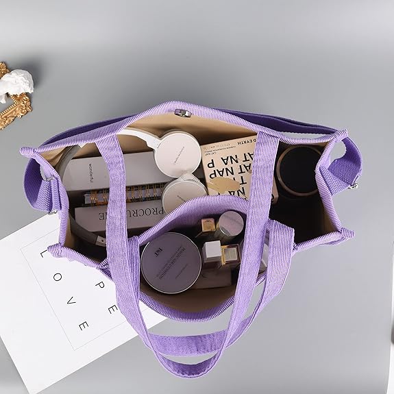 Lila Stofftasche mit Kosmetikprodukten, Büchern und Accessoires, ideal für Reisen und Alltag.