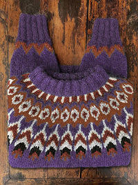 Lila Norwegerpullover aus Wolle mit traditionellem Strickmuster auf Holztisch.