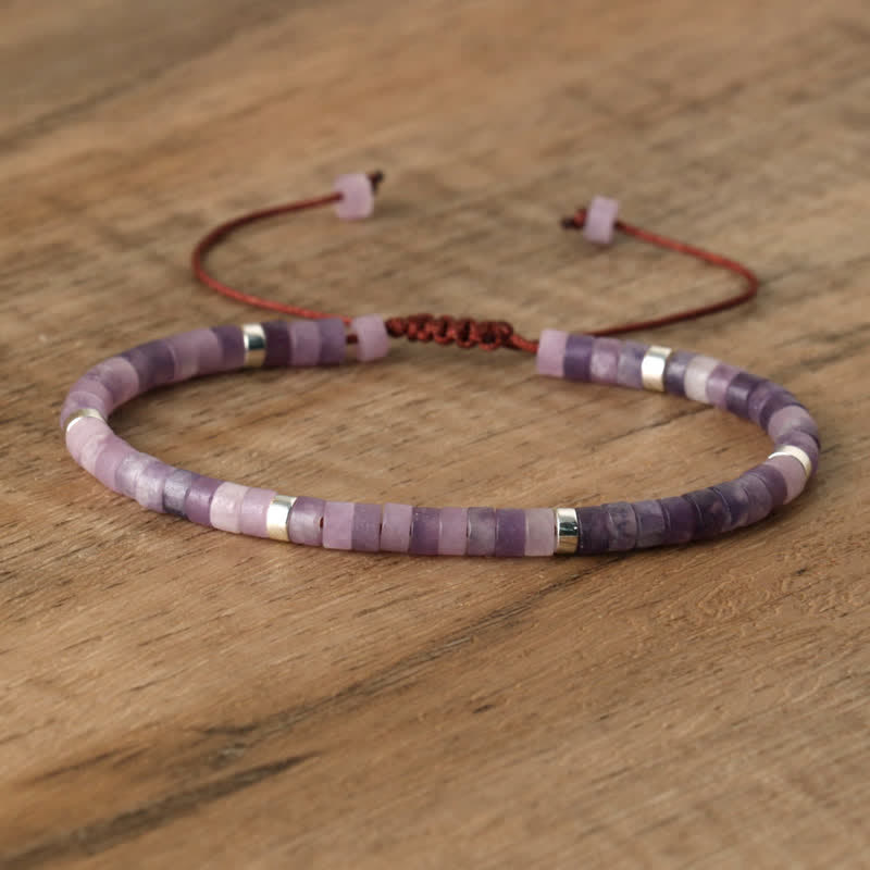 Lila Armband aus Amethystperlen mit verstellbarem Verschluss auf Holzoberfläche.