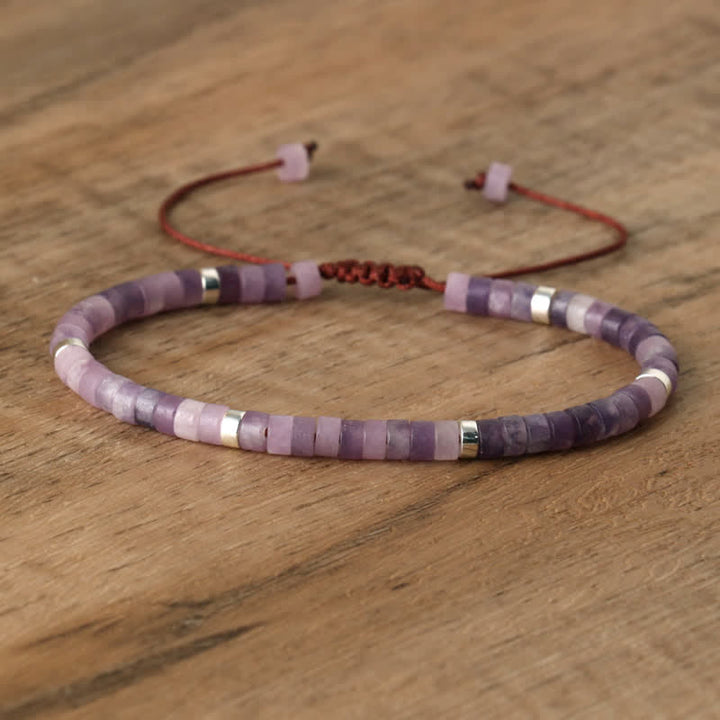 Lila Armband aus Amethystperlen mit verstellbarem Verschluss auf Holzoberfläche.