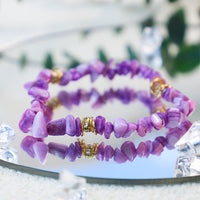 Lila Amethyst-Armband mit goldenen Akzenten, Edelstein-Schmuck, reflektiert auf Spiegel.