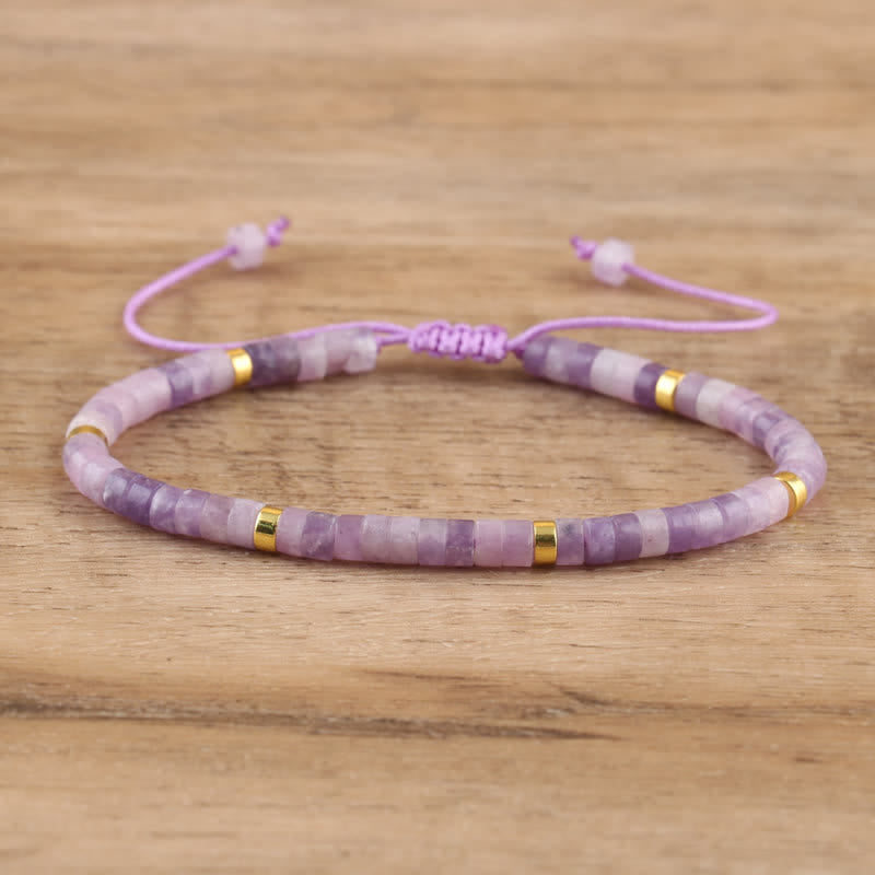 Lila Armband aus Amethyst und Goldperlen, verstellbar, handgefertigt, auf Holzuntergrund.