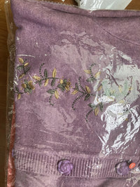 Lila Strickjacke mit Blumenstickerei, Knöpfen, Damenmode, Baumwolle, verpackt in Plastik.