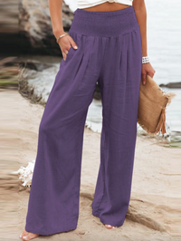 Frau in lila Leinenhose am Strand, Sommermode, lässig, bequem, Damenbekleidung.
